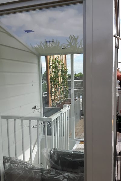 Doorkijk vanuit de woning naar een daktuin met klimplanten tegen een houten scherm