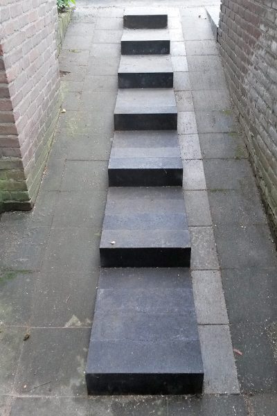 Traptreden van zwarte natuursteen in een bestraat pad tussen twee muren