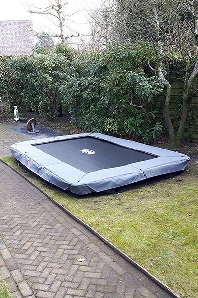 Verdiepte trampoline afgewerkt in het gazon van een achtertuin